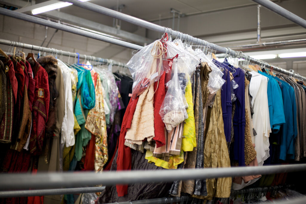 Colourful costumes for theatre hanging on a rail in a storage facility.