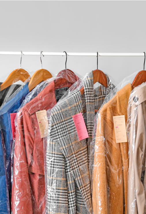 Bright coloured coats on a white clothing rail in plastic after dry cleaning with ozone generator.