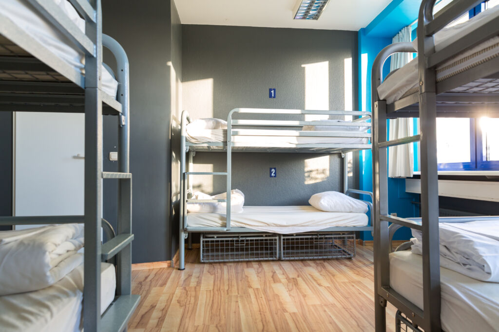 Modern hostel interior with metal bunkbeds and grey walls.