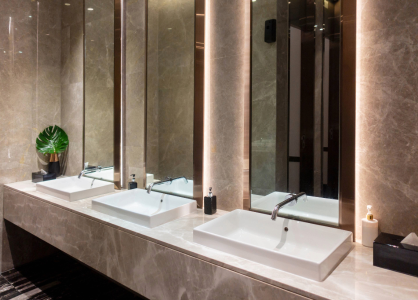 An opulent restaurant bathroom features marble walls and long vertical mirrors.